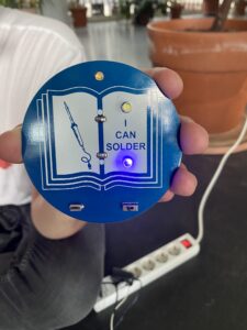 rundes blaues Badge des GPN21-Workshops zum Löten-Lernen mit einem Lötkolben abgebildet und dem Schriftbild "I cab solder" (ich kann löten)